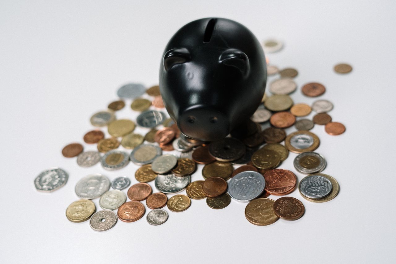 Various coins scattered around a black piggybank
