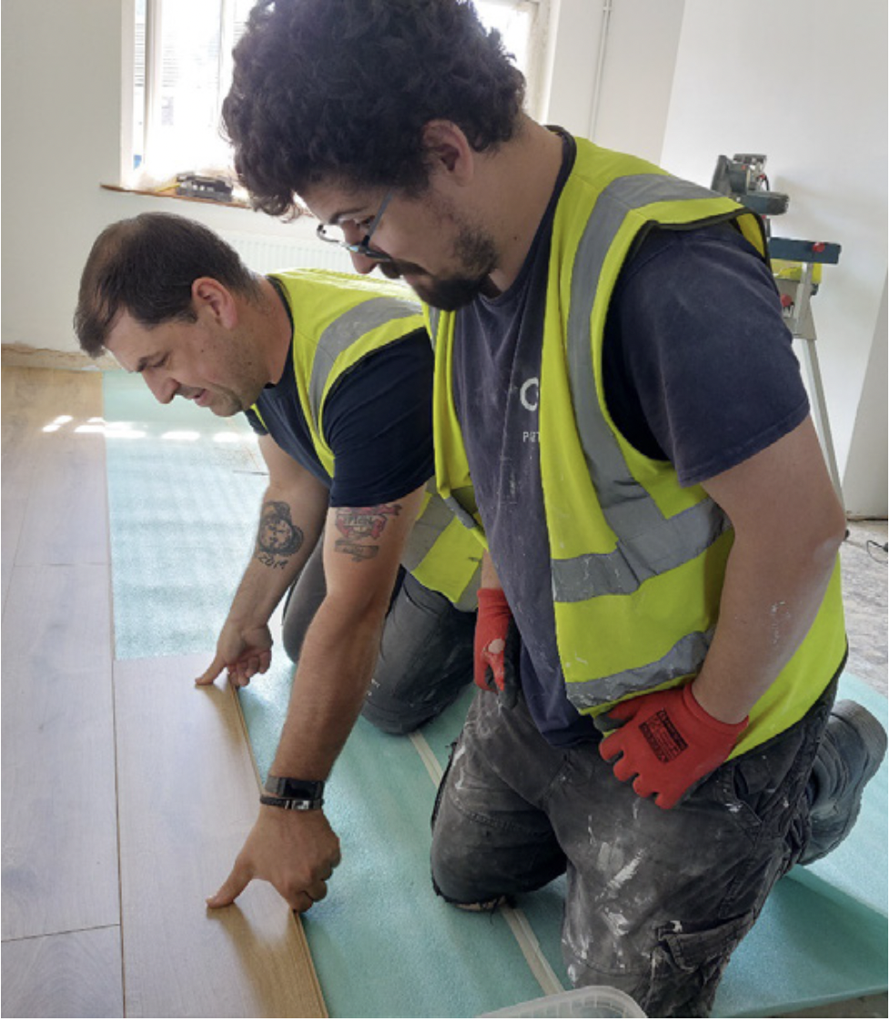 Photo of tutor with apprentice laying flooring